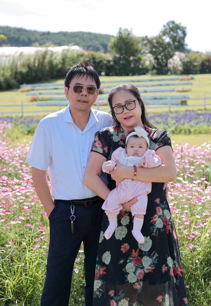 Niềm hạnh phúc của ba mẹ Linh Rin khi bế bồng cháu ngoại giữa cánh đồng hoa rực rỡ. Ảnh: FBNV