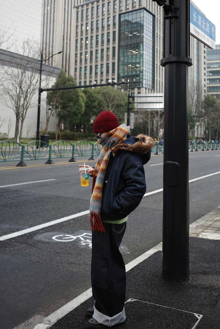 Captain Boy tạo dáng bên lề đường tại Thượng Hải, tay cầm ly nước, ghi lại khoảnh khắc đời thường giữa nhịp sống đô thị hiện đại. Ảnh: FBNV