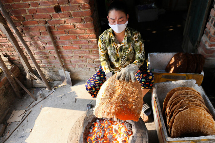 Người làm bánh hơ bánh đa Thổ Hà trên lửa than hoa để nướng hai mặt nóng giòn