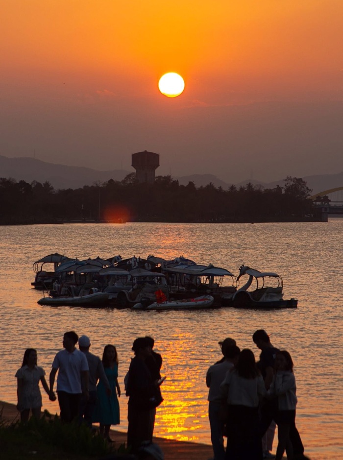 Người dân dạo bước trong khung cảnh sông Hương giữa khoảnh khắc giao thoa của ngày và đêm.