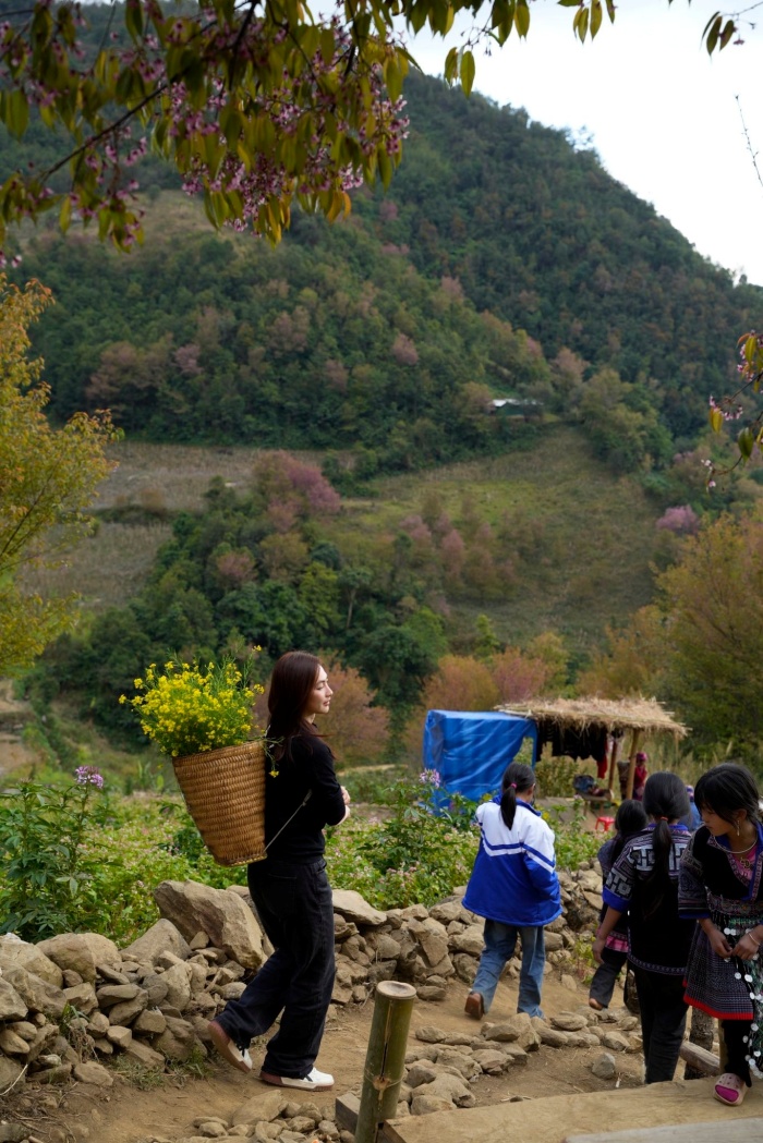 Nụ cười nhẹ nhàng, ánh mắt thân thiện khi trò chuyện với các em nhỏ khiến hình ảnh của cô trở nên tự nhiên và giàu cảm xúc. Những khoảnh khắc ấy không chỉ là kỷ niệm của chuyến đi mà còn mang lại cảm giác bình yên cho người xem.