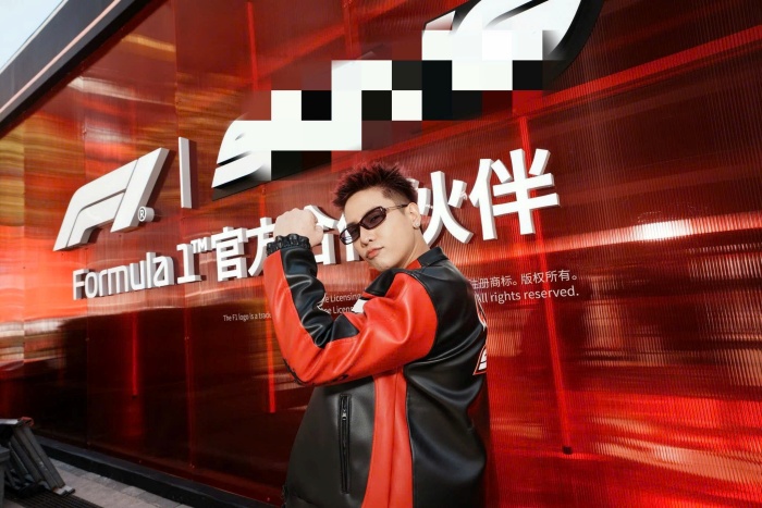 Anh lựa chọn áo khoác da phối hai tông đỏ đen nổi bật, kết hợp cùng kính râm và kiểu tóc nhuộm đỏ bừng cá tính, hòa nhịp hoàn hảo với không khí sôi động của F1, hướng đến tinh thần tốc độ, mạnh mẽ và có phần “nổi loạn”.