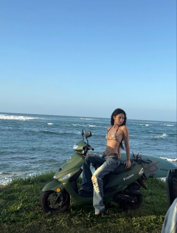 Điểm đặc biệt trong phong cách của Jennie nằm ở cách cô kết hợp khéo léo phối cùng quần jeans rộng chất nhưng vẫn giữ được nét gợi cảm đặc trưng. Sự phá cách khi kết hợp bikini cùng quần jeans rách trên chiếc scooter xanh rêu đã khắc họa nên hình ảnh một quý cô hiện đại, yêu tự do và luôn biết cách làm chủ phong cách cá nhân