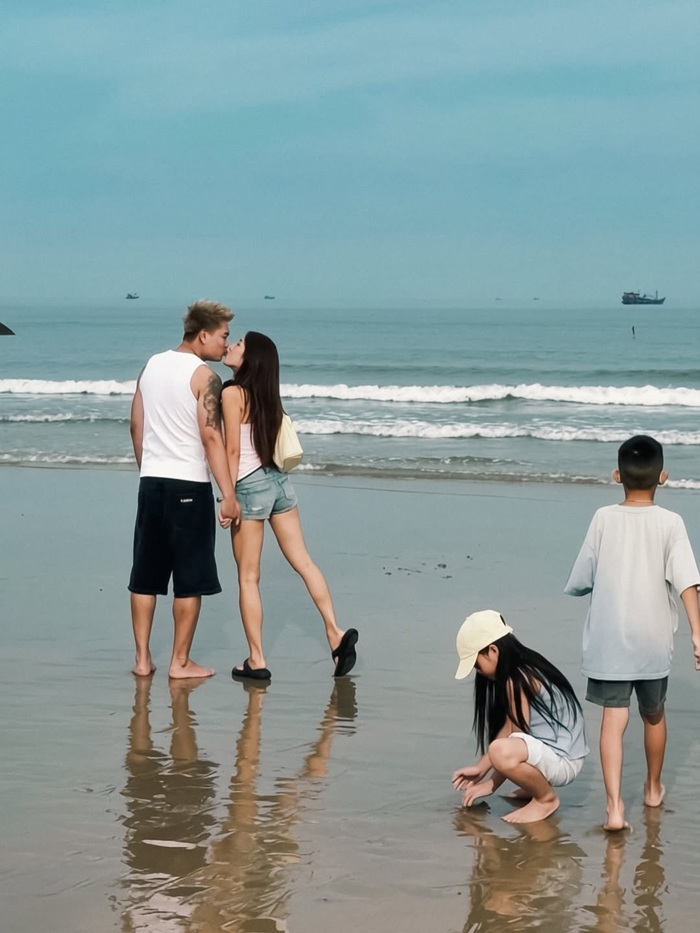Emily và BigDaddy trao nhau nụ hôn ngọt ngào trên bãi biển Hồ Tràm, trong khi hai con vô tư vui đùa. Ảnh: Instagram nhân vật